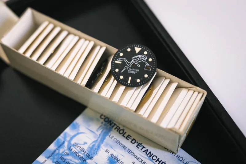 Cadran de montre J. Bianchi sur établi horloger, avec certificat de contrôle d'étanchéité