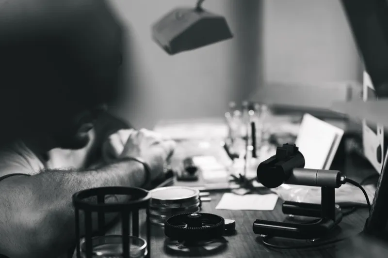 Établi d'horloger en noir et blanc, artisan au travail dans l'atelier Jacques Bianchi