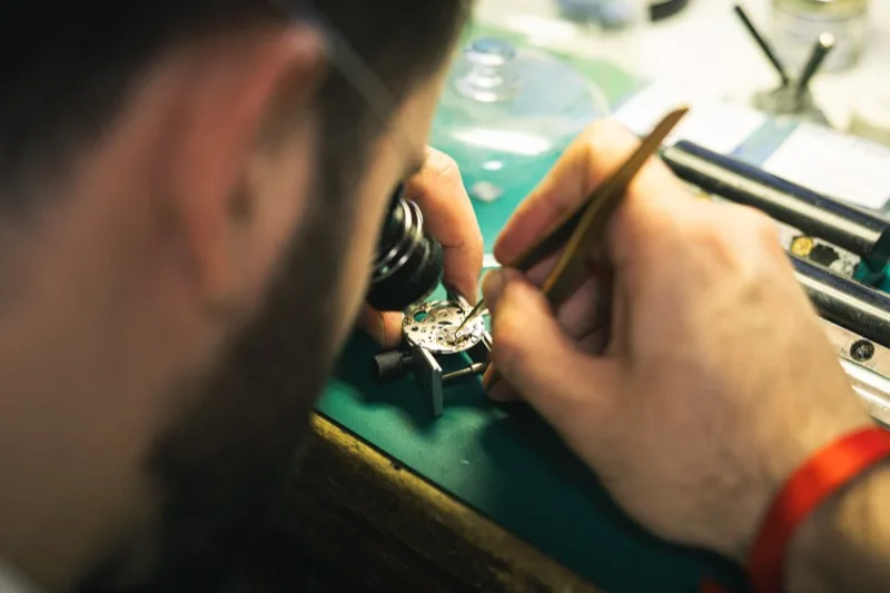 Réparation d'un mouvement mécanique de montre à la loupe, atelier horloger Marseille